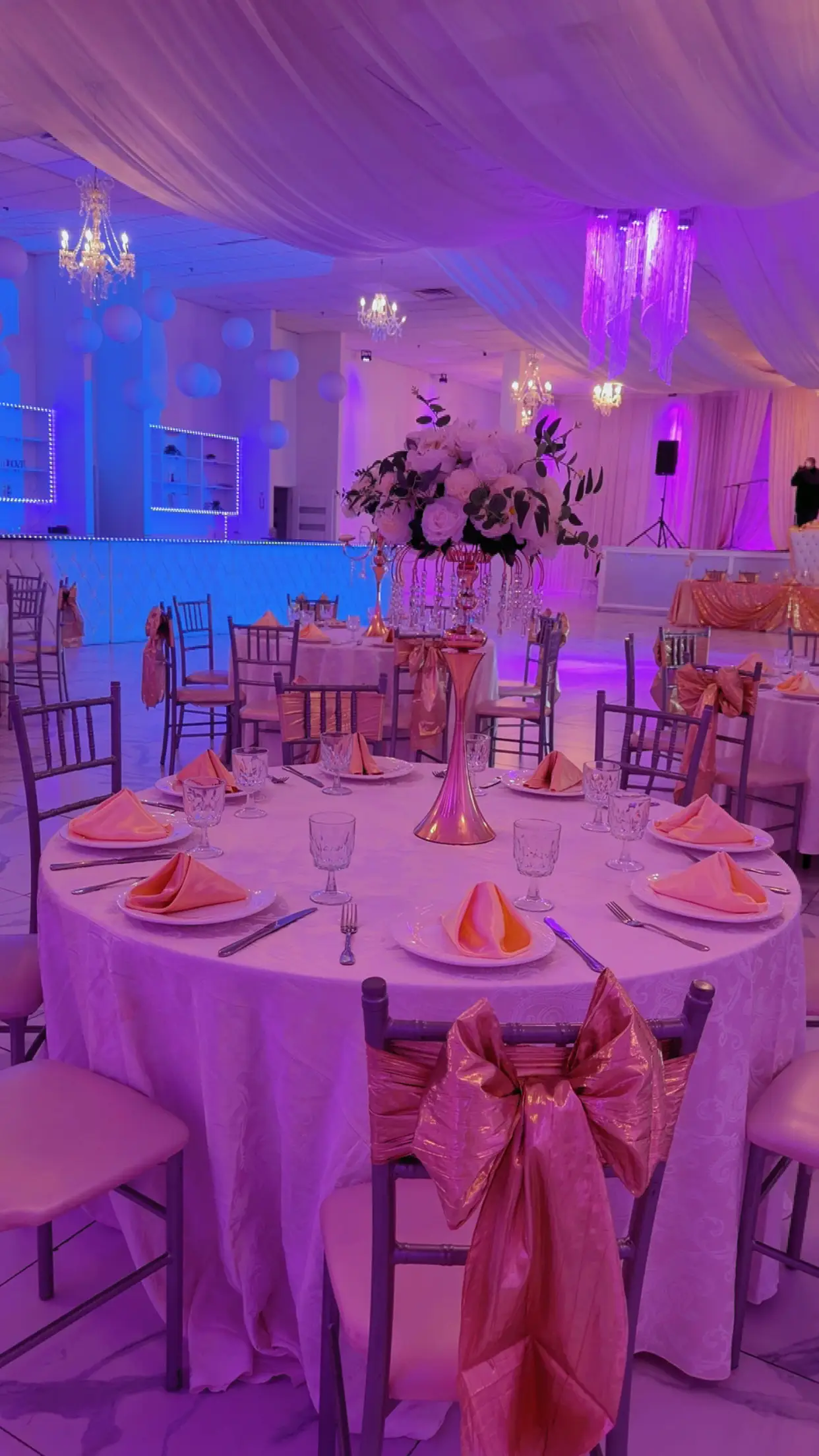 Table set in coral and rose gold under magenta uplighting, with matching napkins and sequined accents